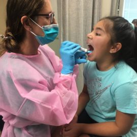 dental hygienist looking into a girl's mouth during dental screening
