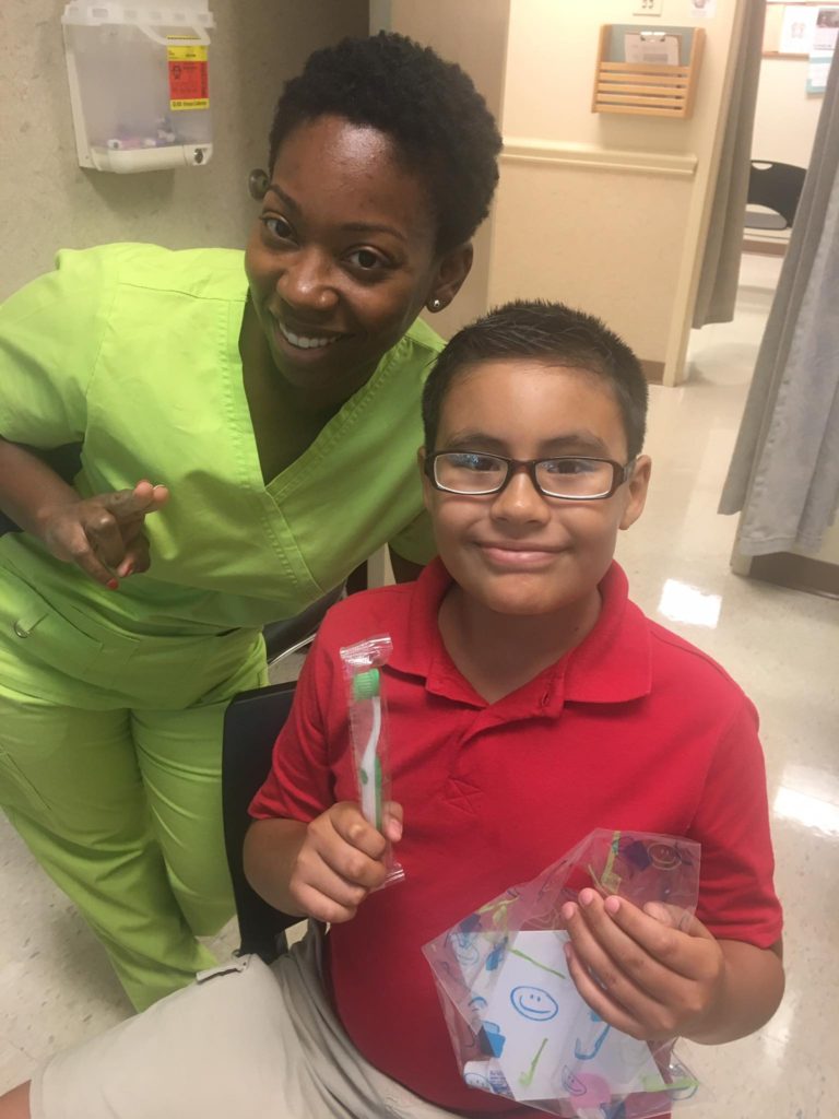 dentist with young boy holding up toothbrush
