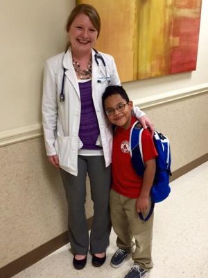 doctor hugs young patient with backpack