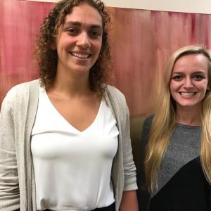 two CCHC interns smiling in front of a painting