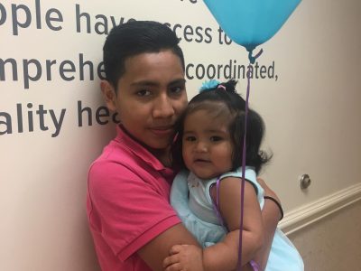 young man holding baby and balloon in clinic