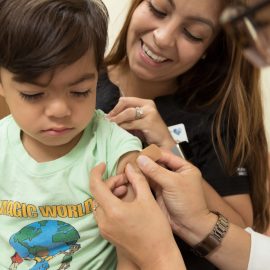 smiling child receives a bandaid after annual flu shot